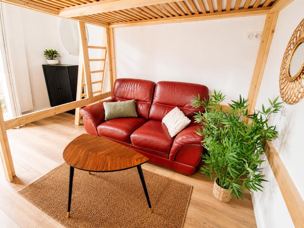 a red leather couch in a living room with a table at Studio cosy avec terrasse - Proche château in Fougères