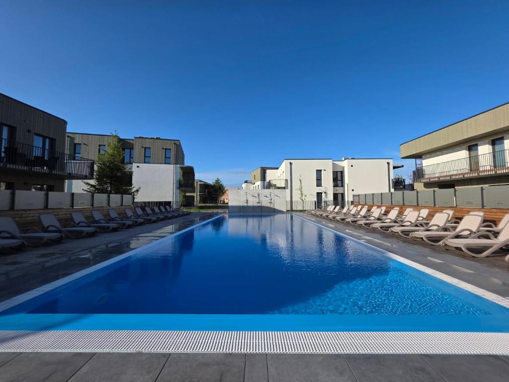 a swimming pool with lounge chairs and blue water at Cozy Home Oasis in Palanga