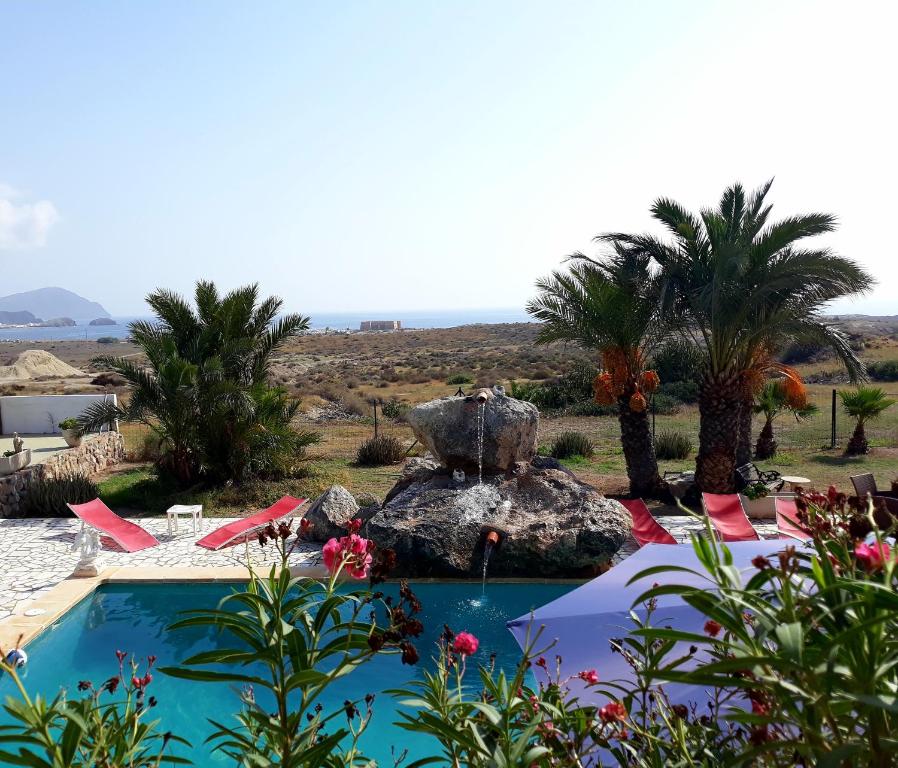 a resort with a pool and palm trees and chairs at El Chalet Los Escullos in Almería
