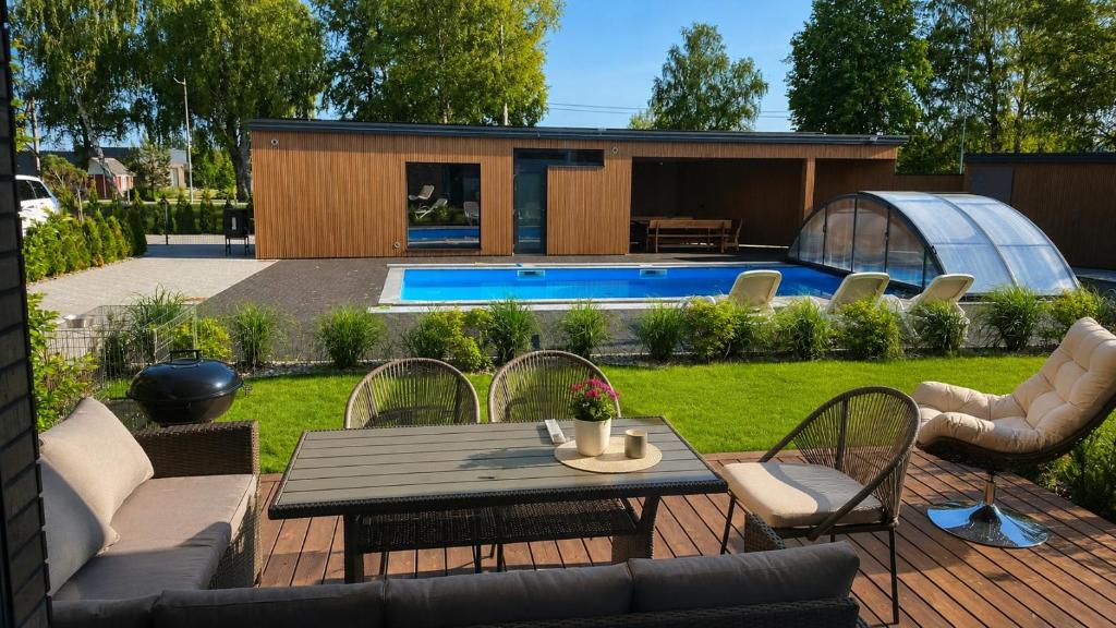 a backyard with a table and chairs and a house at Kotedžas su baseinu ir pirtimi in Palanga