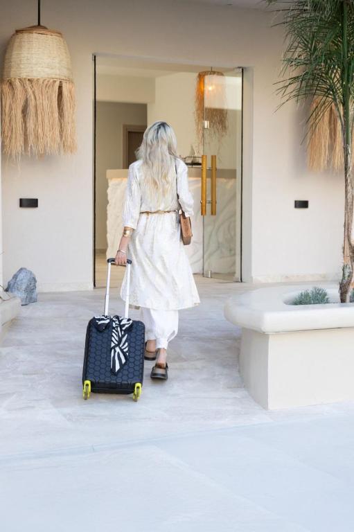 a woman in a white dress pulling a suitcase at MaDaM Essence in Nei Poroi