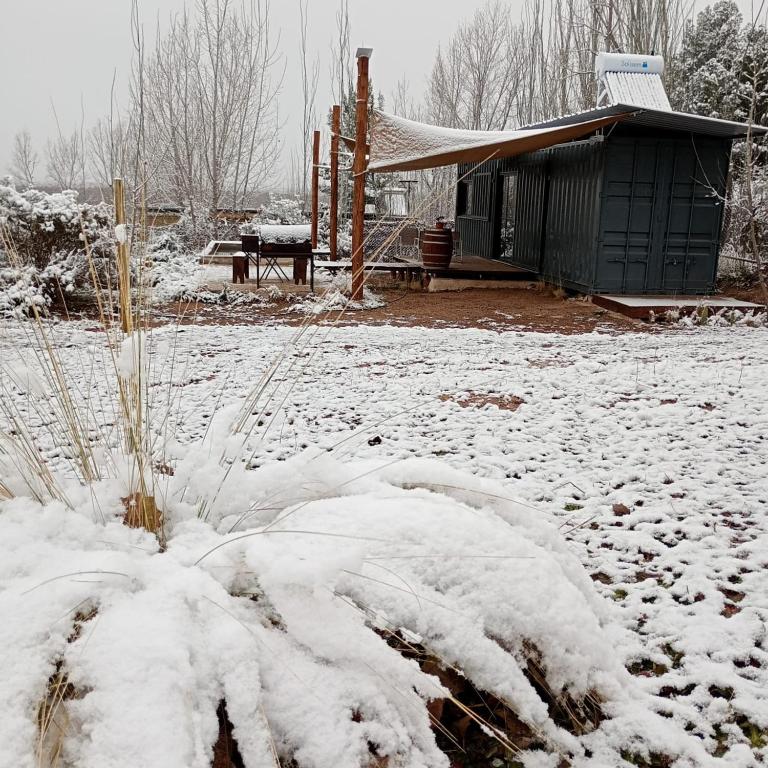 ein schneebedeckter Hof mit einem Schuppen und einem Haus in der Unterkunft Container House in Cacheuta