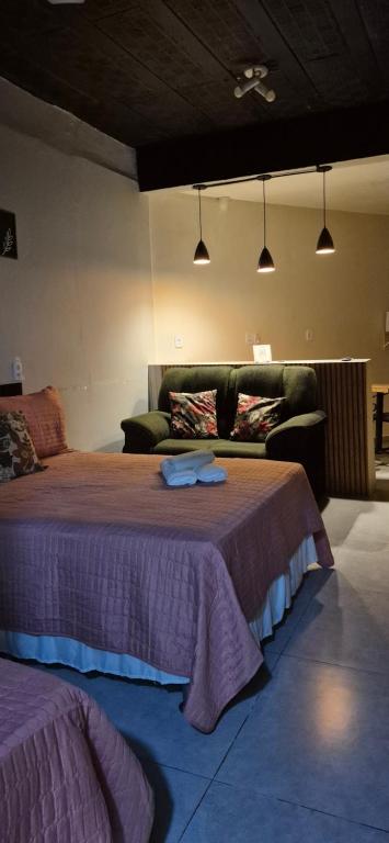 a bedroom with a large bed and a couch at Aconchego I - Centro in Miguel Pereira