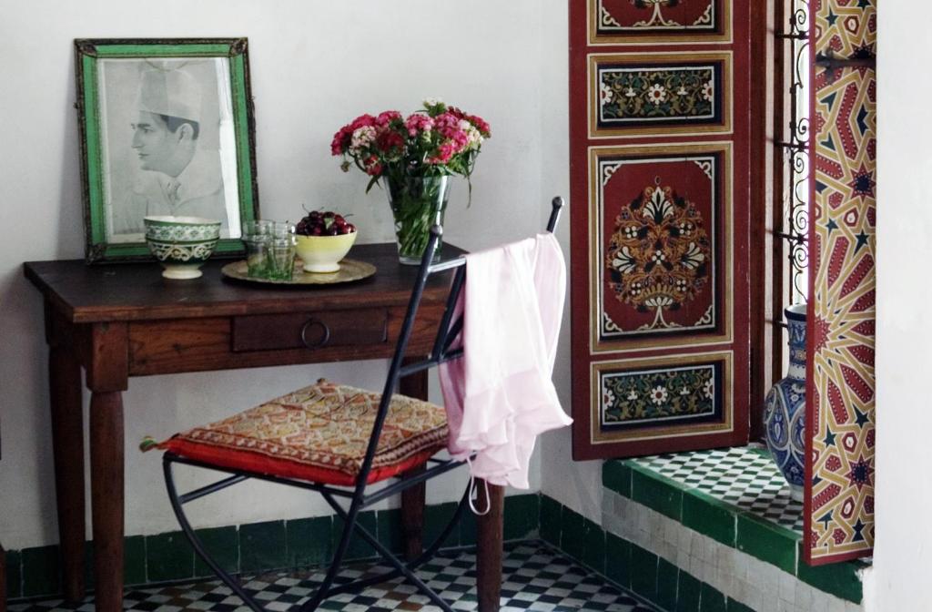 a chair sitting next to a table with a mirror at Dar Seffarine in Fès