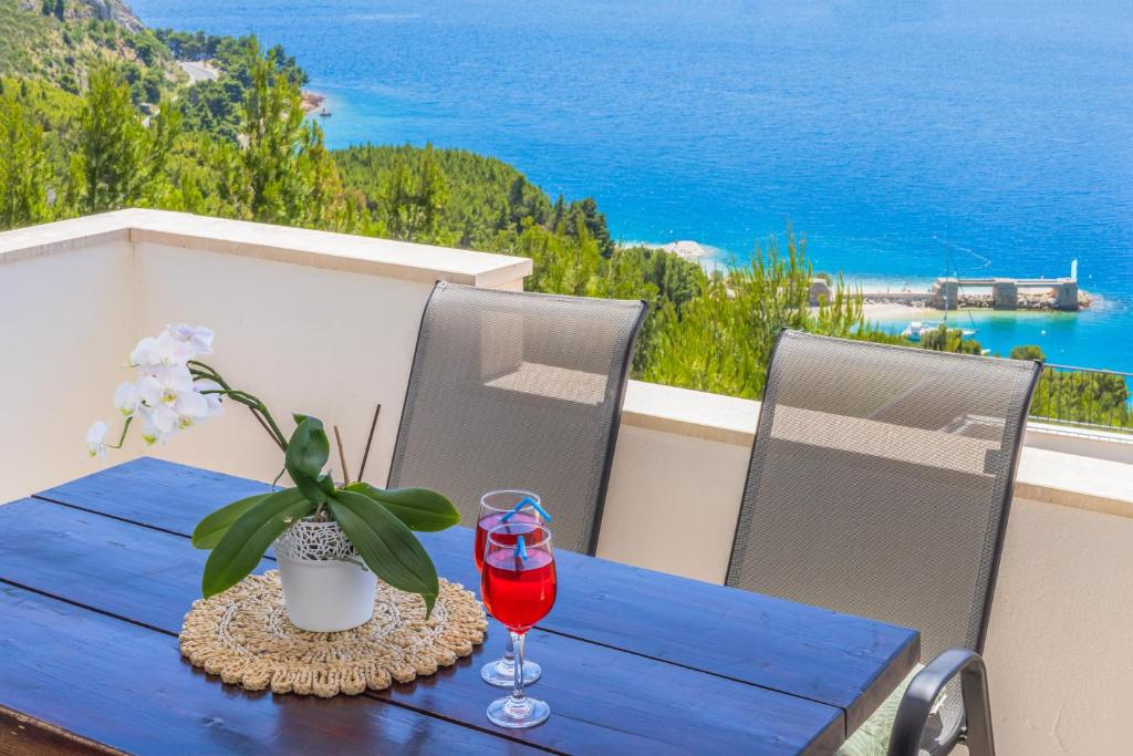 a blue table with a glass of wine on a balcony at White Cove Apartments in Lokva Rogoznica