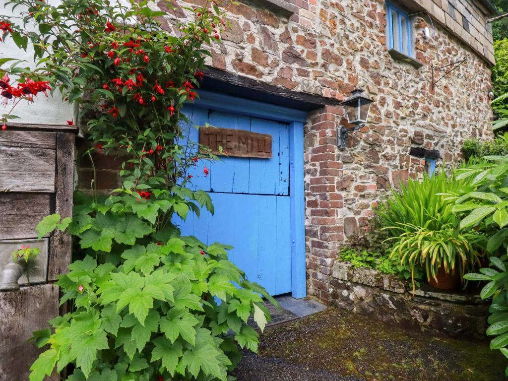 a blue door on the side of a brick building with flowers at The Water Mill at Boyton Mill in Launceston