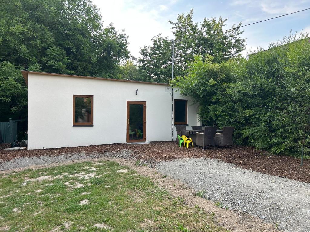 a white building with a table and chairs in a yard at Prázdninový domeček in Heřmanice