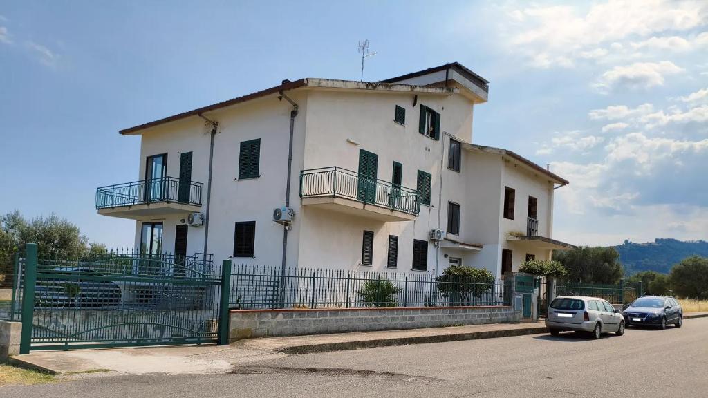 a white building with cars parked in front of it at Affittacamere Domus Roseto in Roseto Capo Spulico