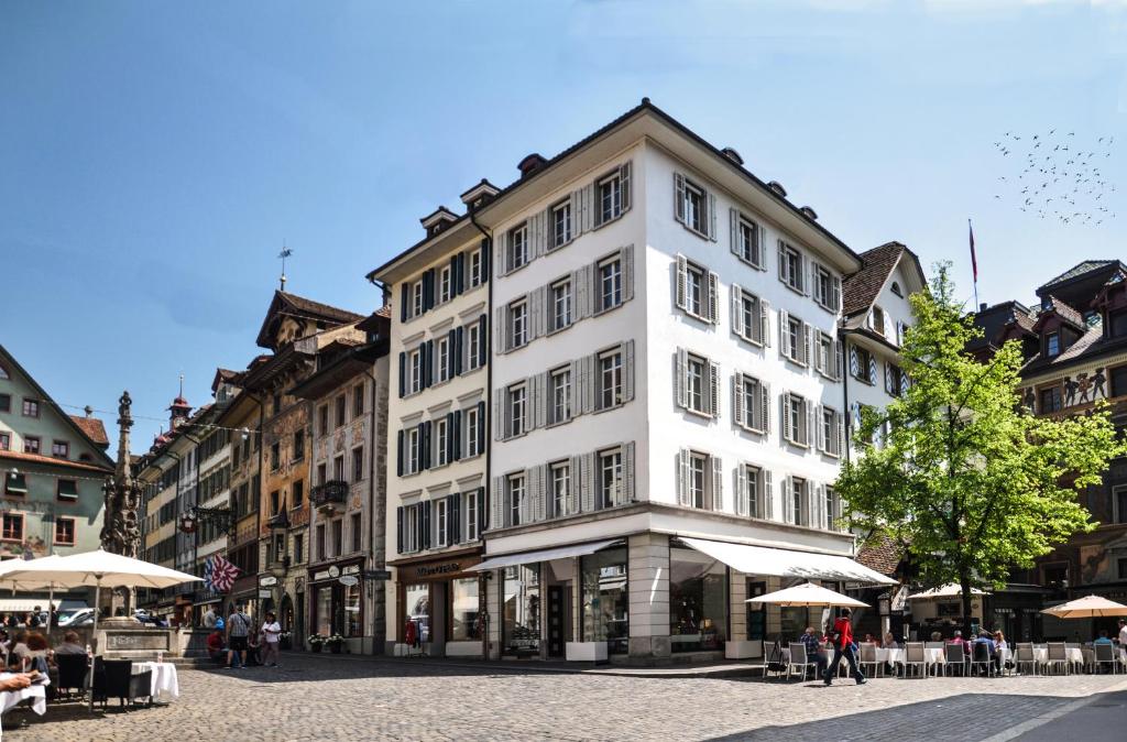 a large white building on a street with tables and umbrellas at ODA Suites - self check-in apartments, old town in Lucerne