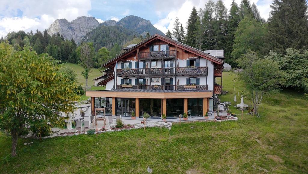 a large house on a hill with mountains in the background at Rifugio Caltena in Fiera di Primiero
