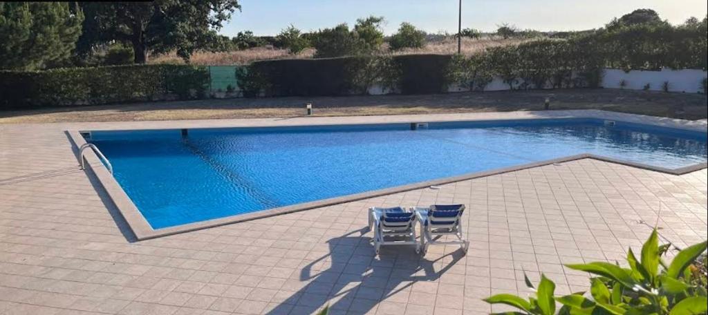two chairs sitting in front of a swimming pool at Quinta dos Crastos Pool House in Porches