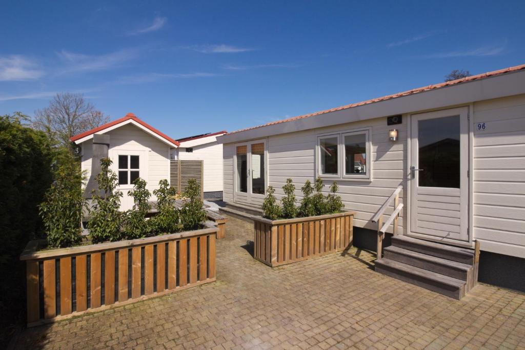 een tiny house met een veranda en een aantal planten bij Chaletparc Krabbenkreek in Sint Annaland