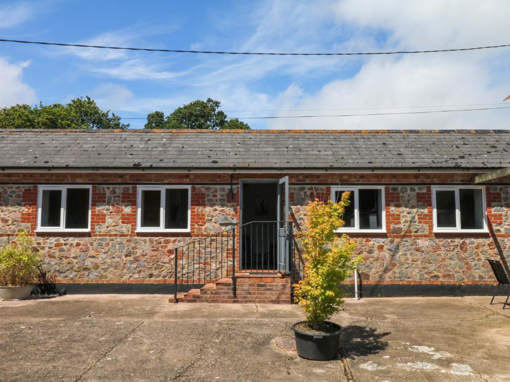 a brick house with a black door at The Milk Shed in Plymtree