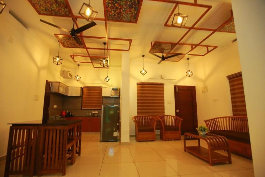 a living room with a kitchen with chairs and tables at AJ Homes - Aaron Villa in Ernakulam