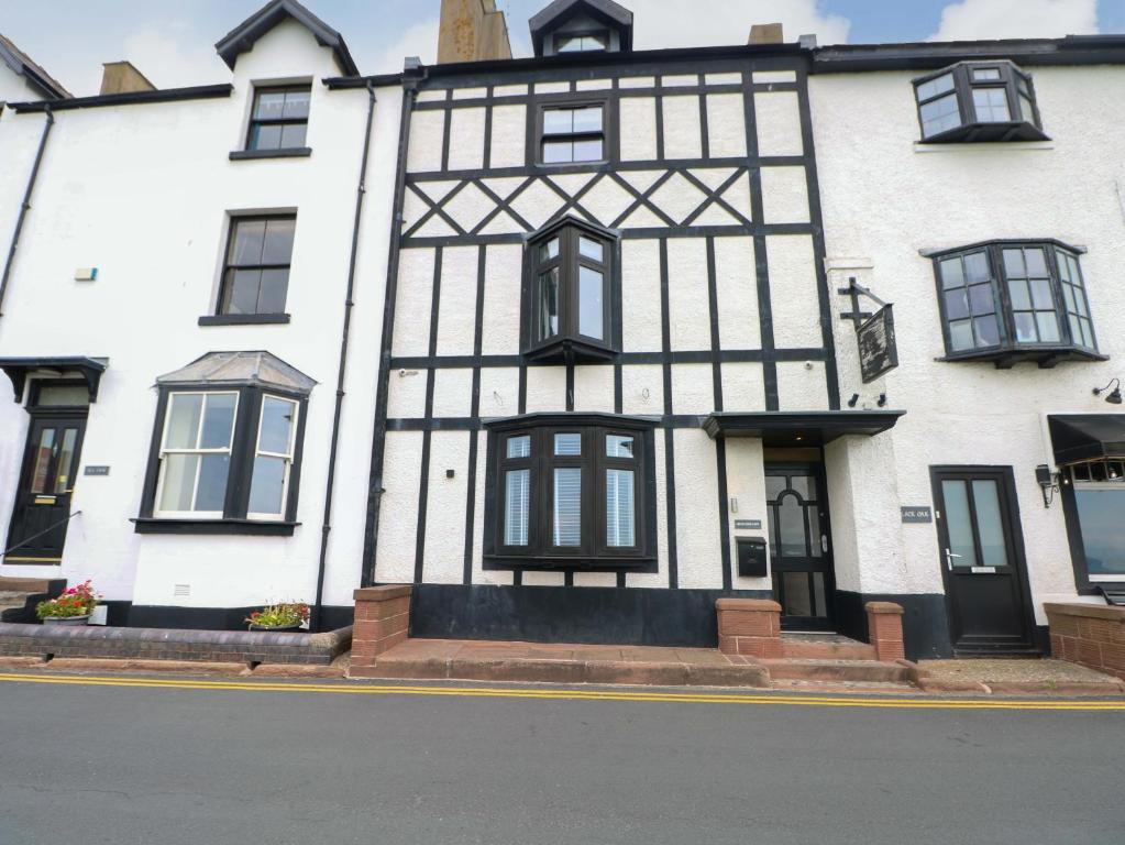 a white building with black windows on a street at Broad Beams in Neston