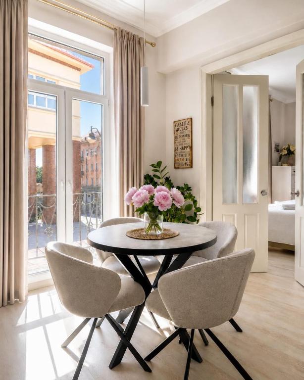 a dining room table with chairs and a vase of flowers at Stylish air-conditioned Klaipeda Flat, Near Dane River in Klaipėda