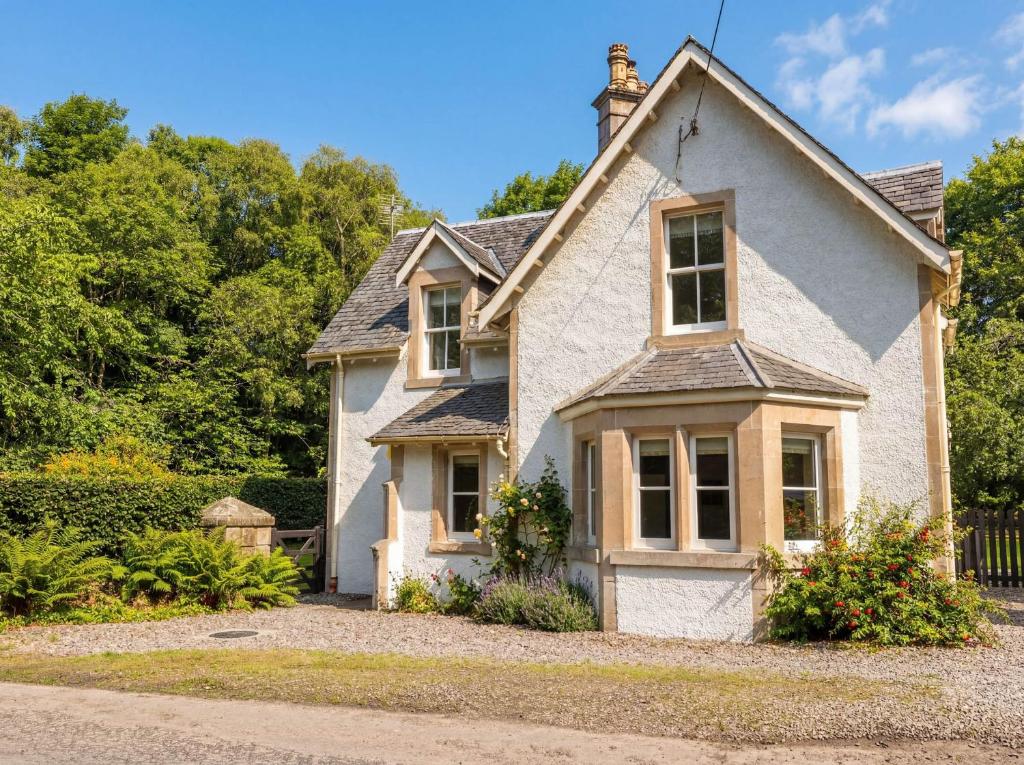 a white house with a fence and trees at Station Lodge in Forres