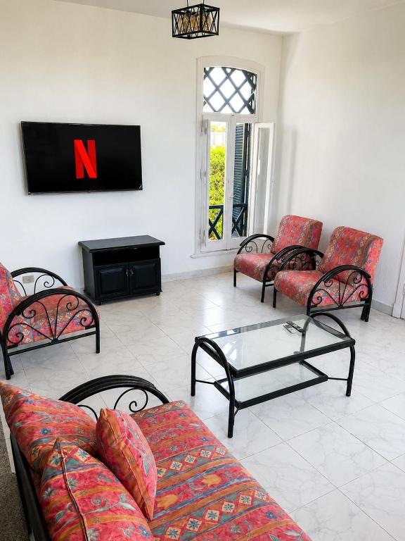 a living room with couches and a tv on the wall at Charming 3BDR Chalet l North Coast in Dawwār Muşādif Yūnus