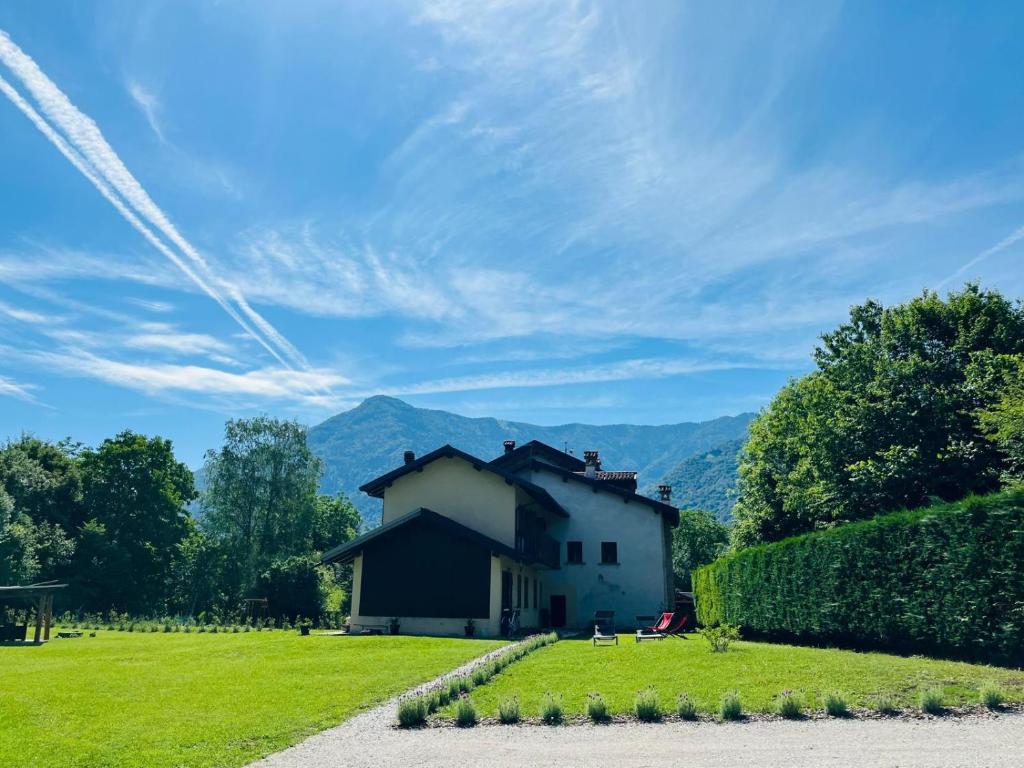 a house in a field with mountains in the background at Il giardino in campagna in Seren del Grappa