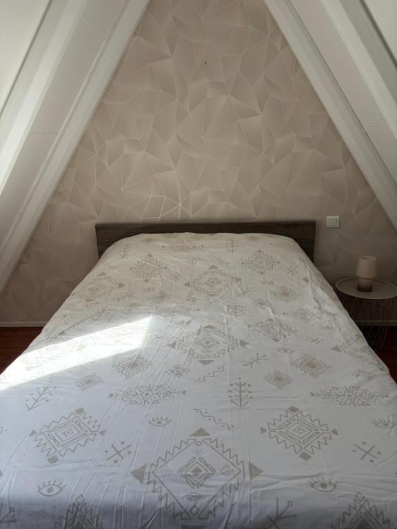 a bedroom with a bed with a white comforter at Chalet 6 à 8 personnes in Drulhe