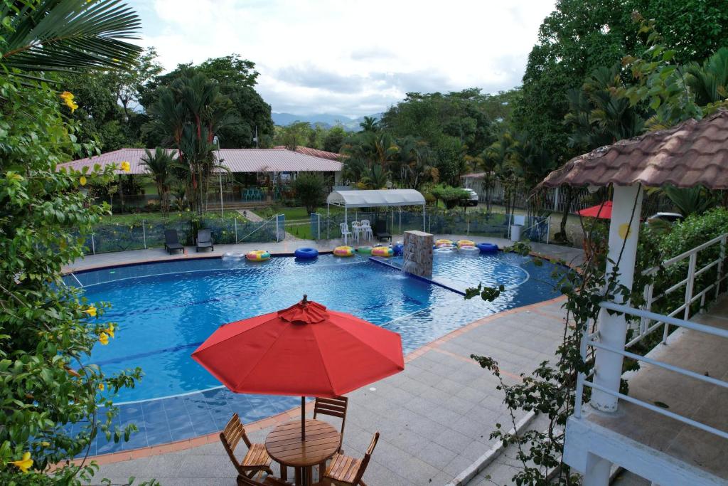 a red umbrella sitting next to a swimming pool at Finca Hotel La Potranca in Acacías