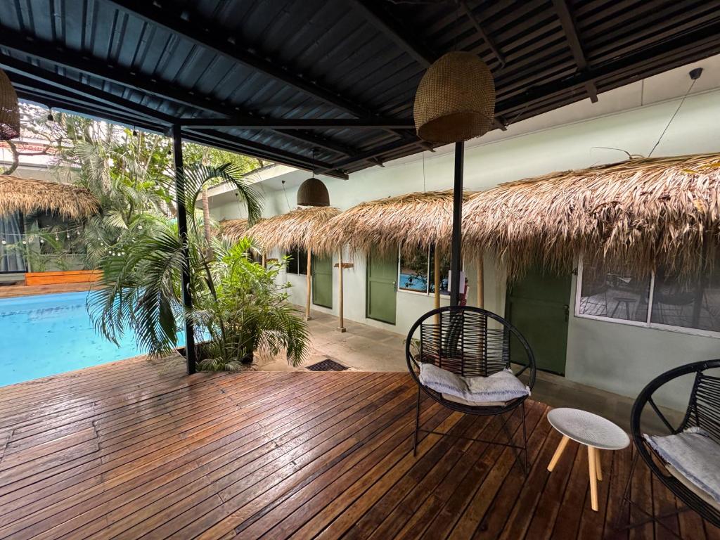 a wooden deck with chairs and a swimming pool at Refugio Surf Lodge in Tamarindo