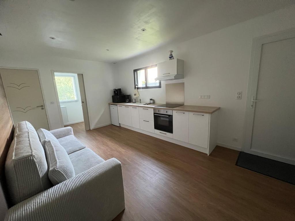 a living room with a couch and a kitchen at Studio indépendant à notre maison in Concarneau