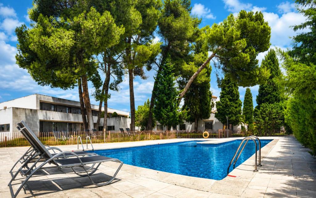 a chair next to a swimming pool with trees at Hotel & Spa La Salve in Torrijos