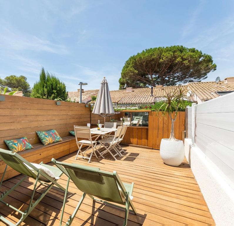 a patio with a table and chairs on a wooden deck at Villa 52 Naturiste in Cap d'Agde