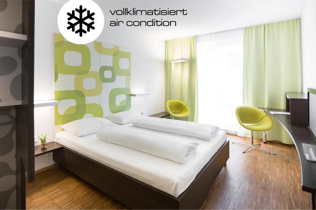 a bedroom with a bed and two yellow chairs at arte Hotel Krems in Krems an der Donau