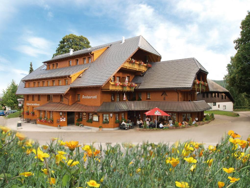 黑森林貝爾瑙的住宿－Naturparkhotel Schwarzwaldhaus，一座大型的木质建筑,前面有鲜花