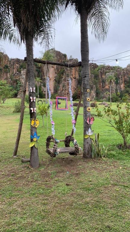 a swing in a park with two palm trees at Villa Virgen De La Gracia in Tobatí