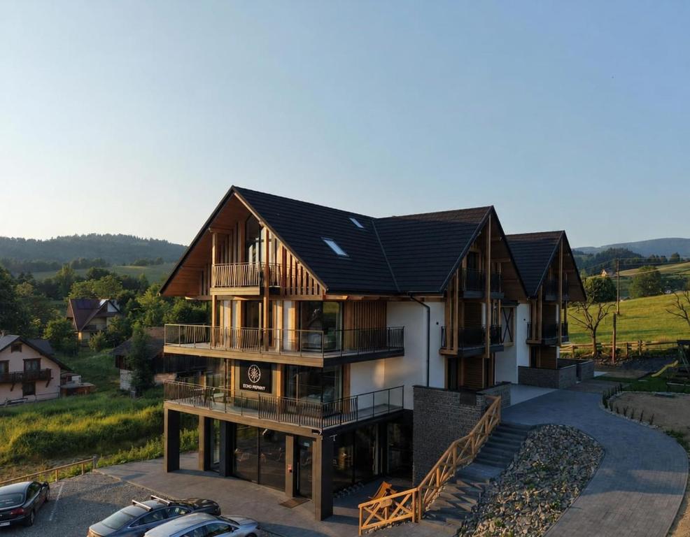 a house with a black roof with cars parked in a parking lot at Apartamenty Etno Pieniny in Jaworki