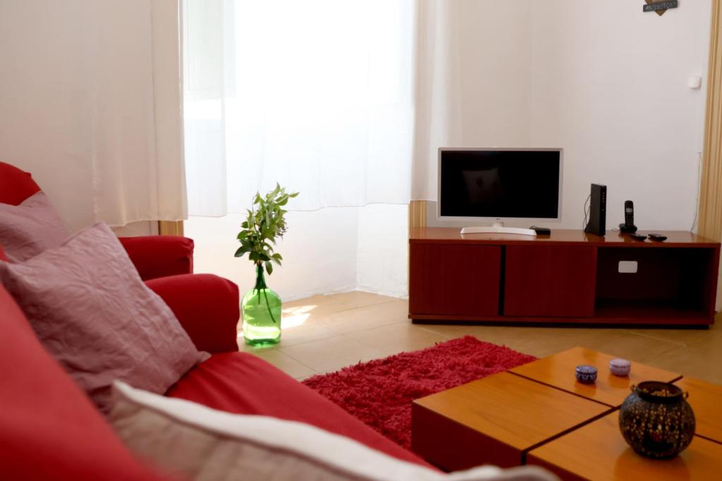 a living room with a red couch and a tv at Recanto do Capucho in Conceição