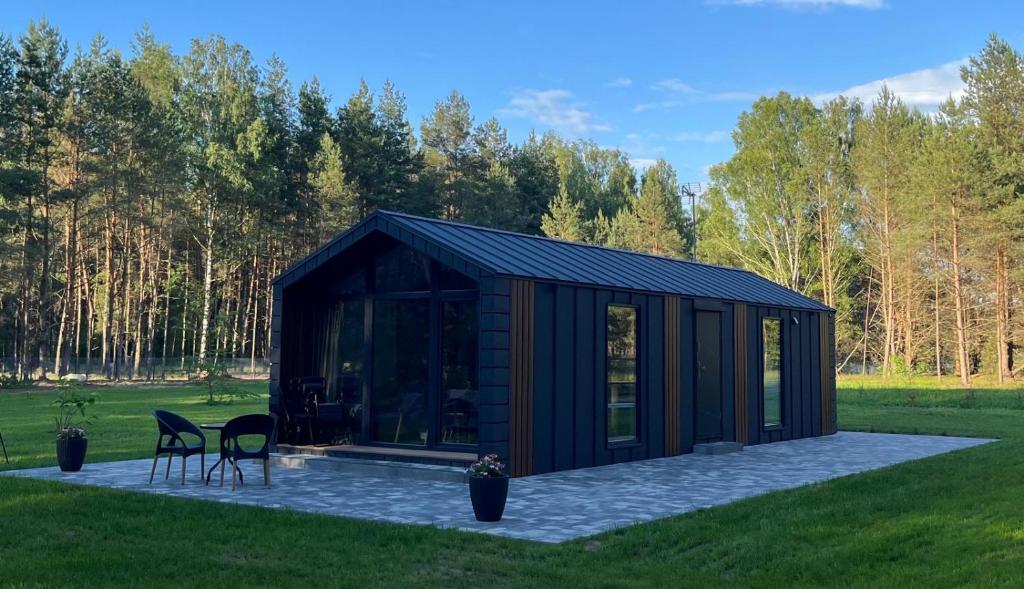 a black shed with a patio in the grass at Domek pod brzozami in Waszki