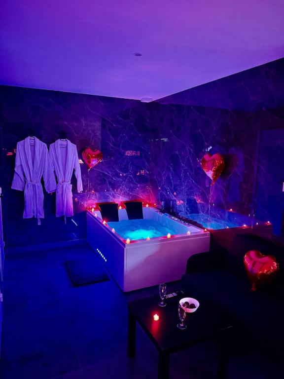 a jacuzzi tub in a room with purple lighting at Rochetaillée Secret Spa in Saint-Étienne