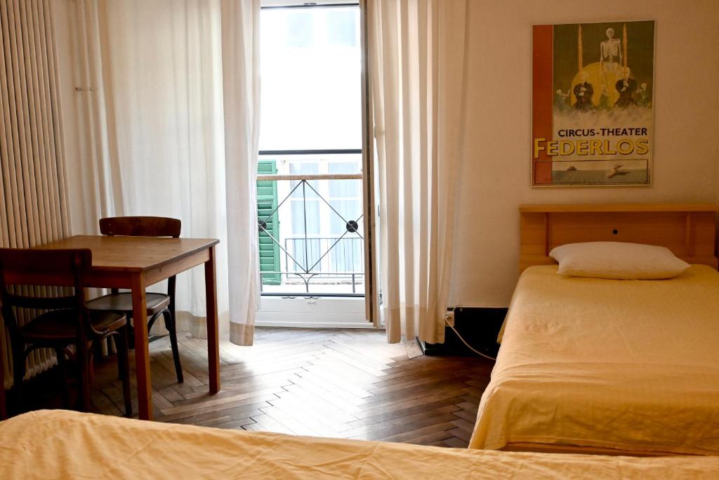 a bedroom with two beds and a table and a window at Hotel Genossenschaft Kreuz in Solothurn