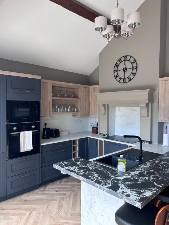 a kitchen with blue cabinets and a clock on the wall at Creagh Road House in Ballinrobe