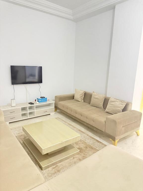 a living room with a couch and a flat screen tv at Aouina Stay in El Aouina Station