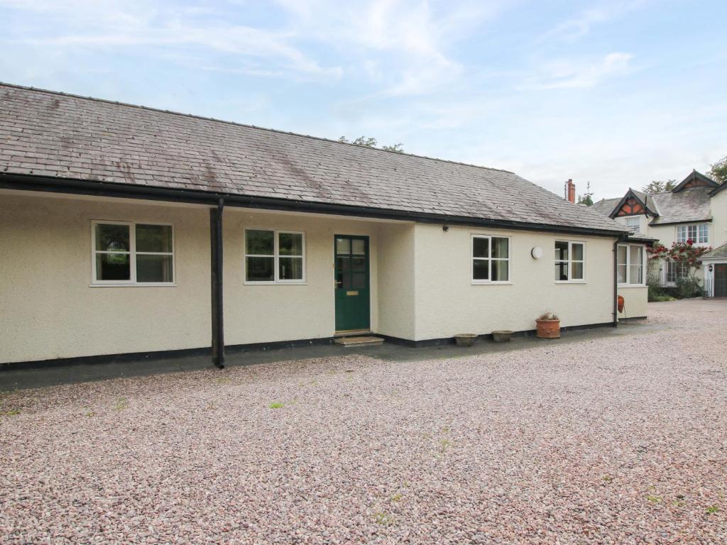 a white house with a green door and a driveway at Willow Cottage in North Lydbury