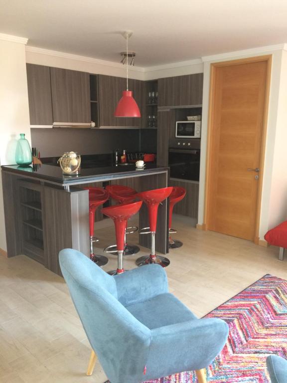 a kitchen with red bar stools and a blue chair at Solvallerios Viña Centro in Viña del Mar