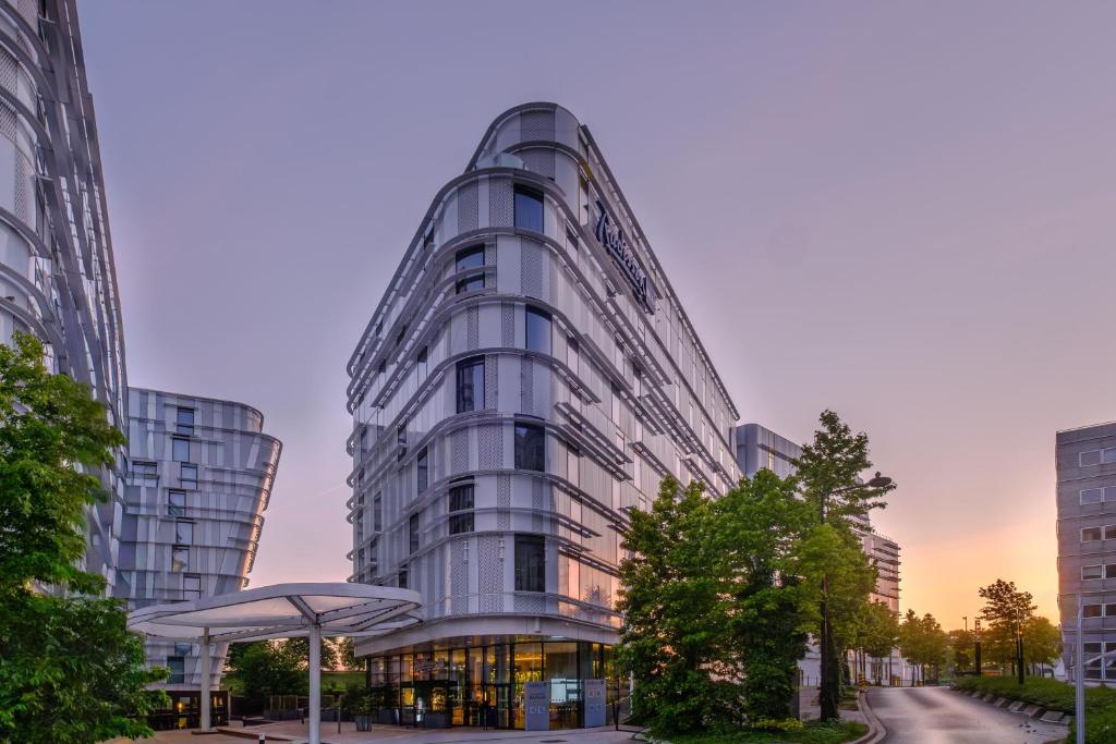 a tall glass building in a city at Radisson Blu CDG Airport Terminal Hotel, Paris in Tremblay-En-France