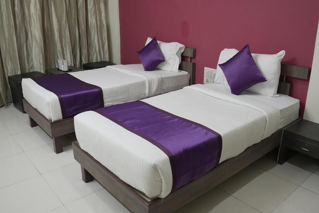 two beds in a room with purple and white at Hotel highway inn in Gandhidham