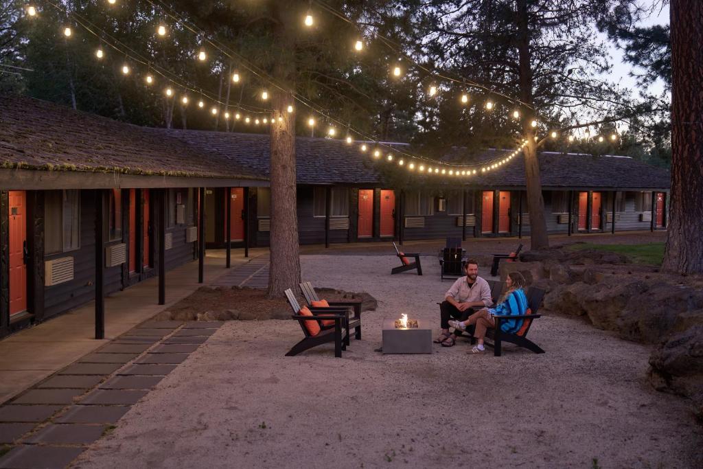 two people sitting on benches under string lights at Trailhead Lodge in Bend