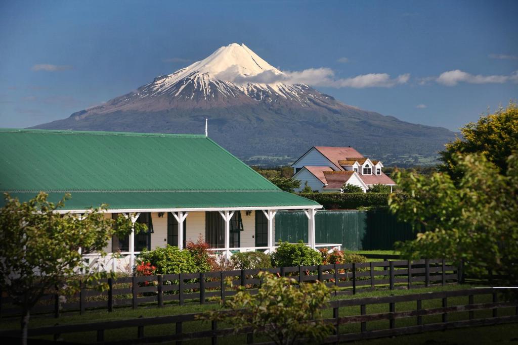 a mountain behind a house with a green roof at Kerry Lane Motel in Hawera