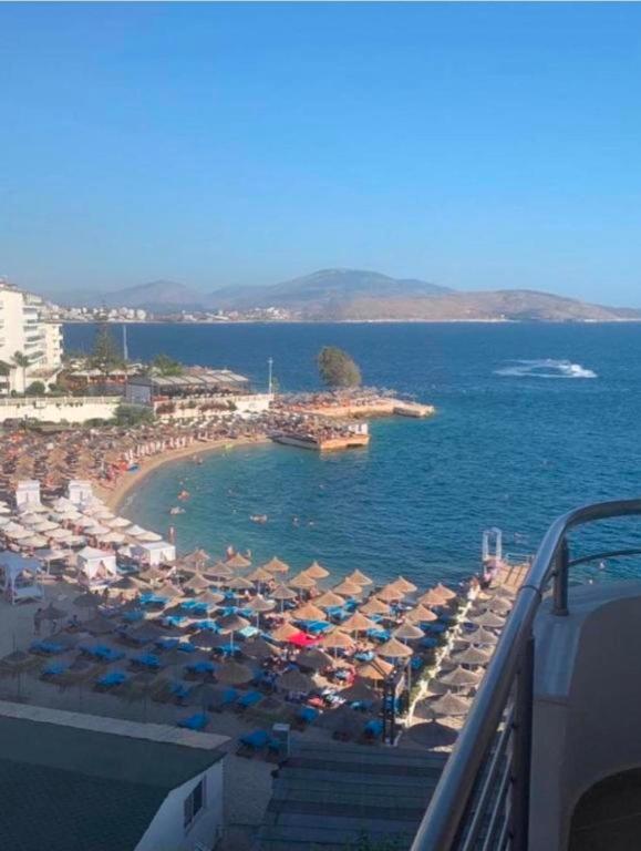 a beach with umbrellas and people in the water at Βeachfront Luxury Apartments SARANDE in Sarandë