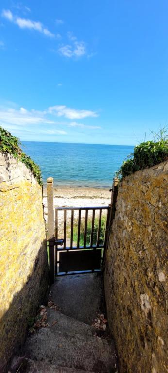 a stairway to the beach with the ocean in the background at Duplex les pieds dans l'eau in Grandcamp-Maisy