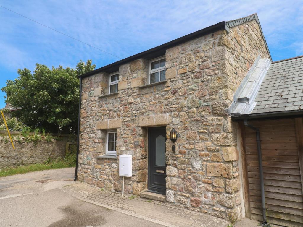 a stone house with a sign in front of it at Gews Farm Lodge in Penzance