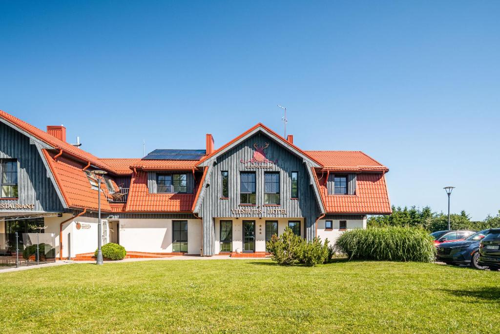a house with an orange roof and a yard at Gamtos Perlas in Karklė