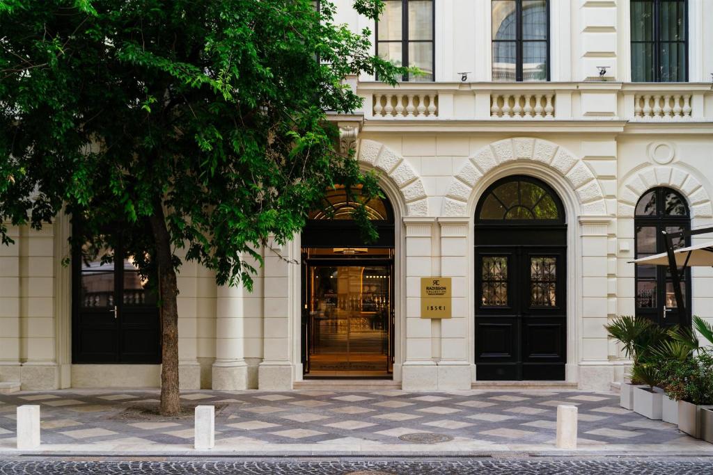 a building with two black doors and a tree at Radisson Collection Hotel, Basilica Budapest in Budapest
